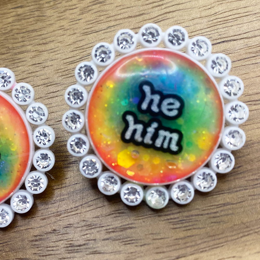 White rhinestone glowing rainbow pronoun pins with she/her label. Handmade in Melbourne by iridian.design.